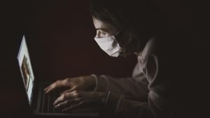 Woman wearing a PPE mask while working on a computer