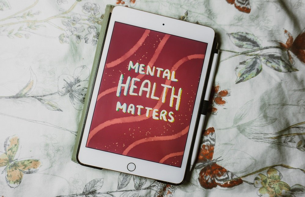 An ipad on a flower patterned bedspread, displaying the message 'Mental health matters'