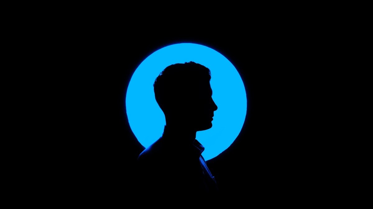 A black silhouette of a man's profile against a bright blue circle