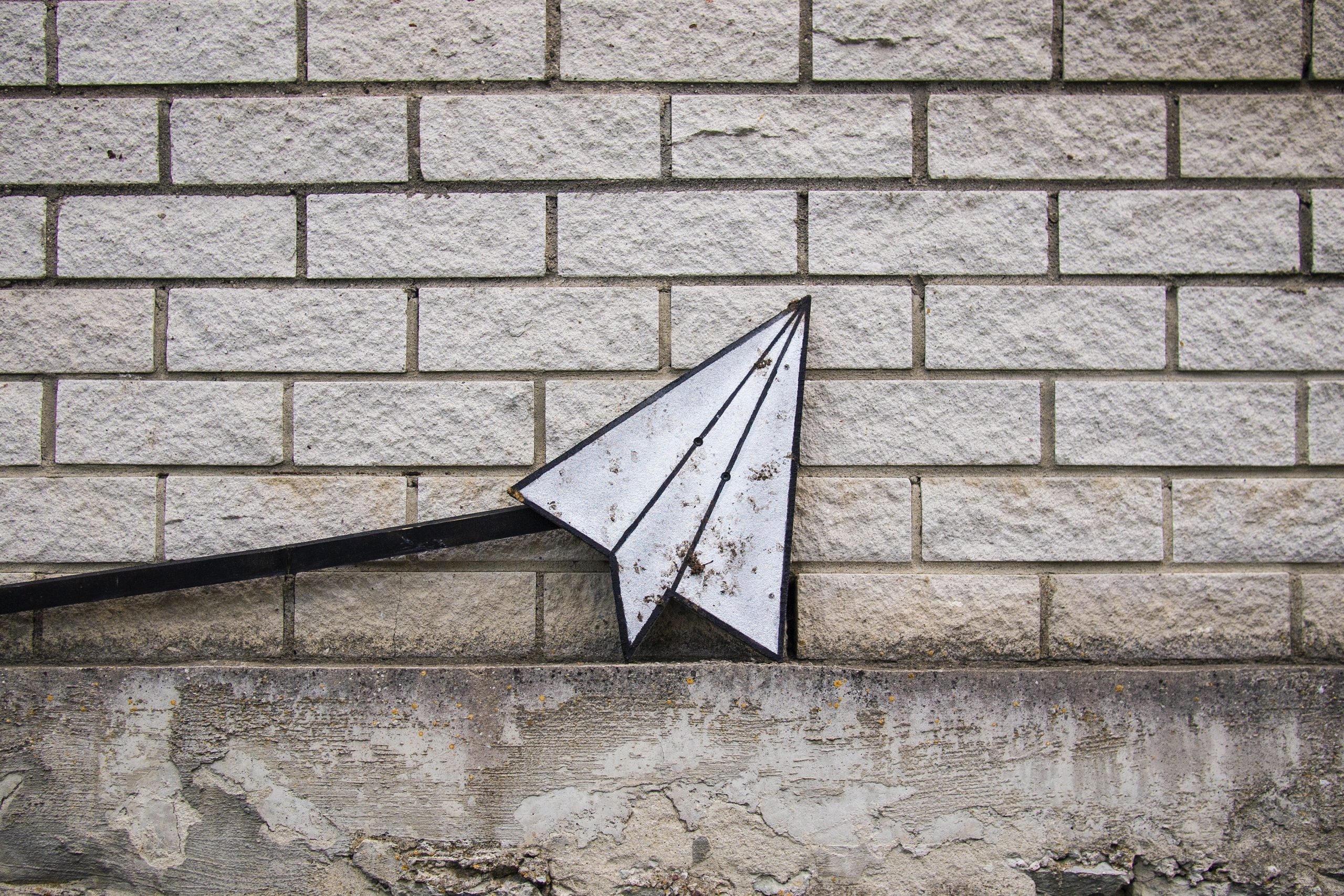 Paper airplane icon against a brick wall