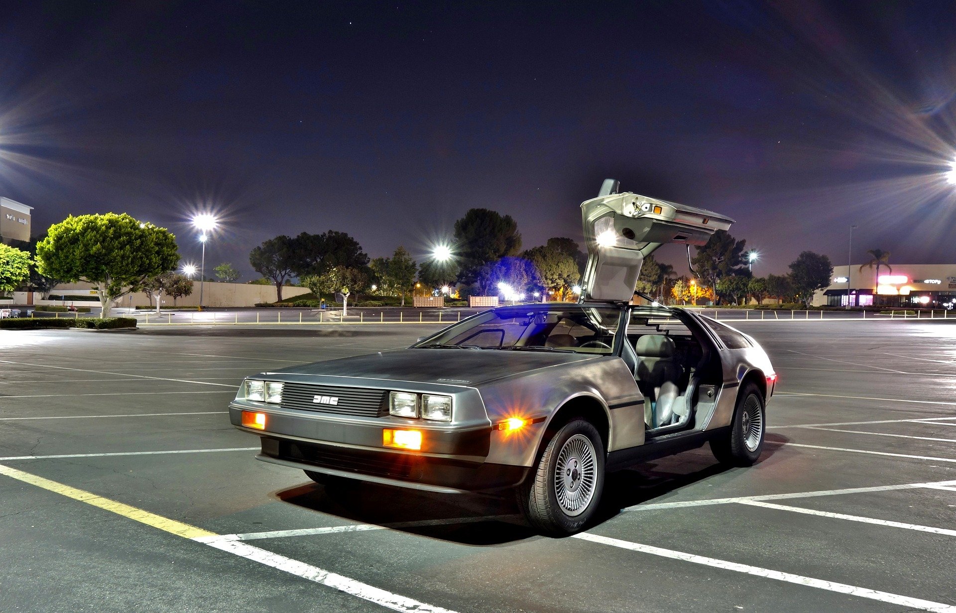 DeLorean time machine in an open air car park at night, with one door open